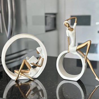 Statujë vajze që lexon libër me forma gjeometrike