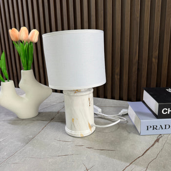 Llambë tavoline me bazë qeramike formë cilindrike dhe abazhur tekstili